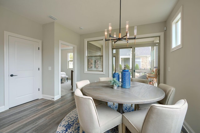 dining area featuring dark hardwood / wood-style floors and an inviting chandelier