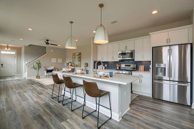 kitchen with ceiling fan, hardwood / wood-style floors, white cabinets, and appliances with stainless steel finishes