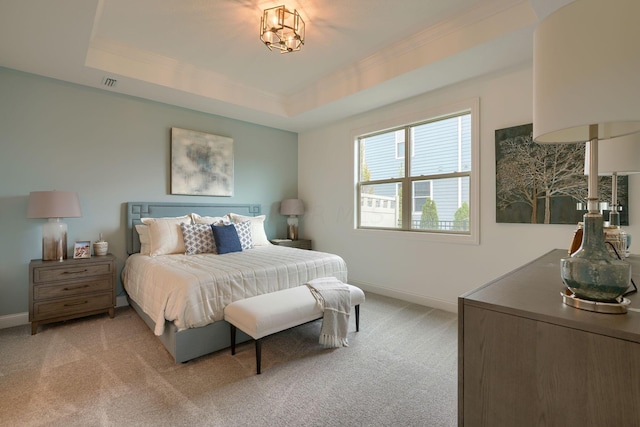 carpeted bedroom featuring a raised ceiling and a chandelier