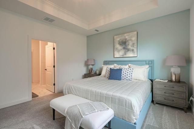 carpeted bedroom with a tray ceiling, ensuite bath, and ornamental molding