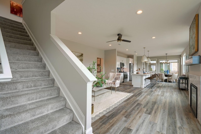 staircase with wood-type flooring and ceiling fan