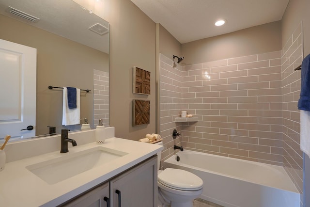 full bathroom with a textured ceiling, vanity, toilet, and tiled shower / bath