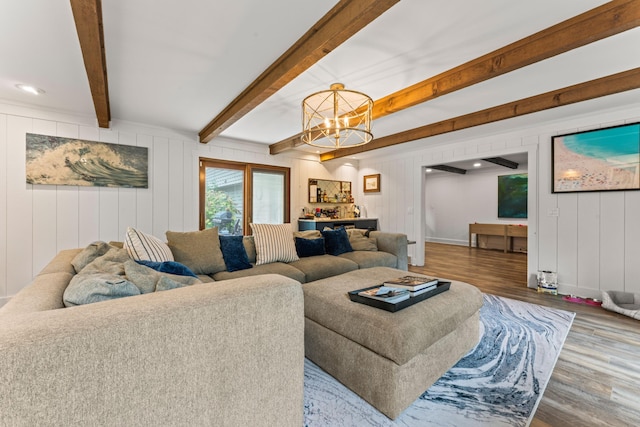 living room featuring hardwood / wood-style flooring, wooden walls, beamed ceiling, and a notable chandelier