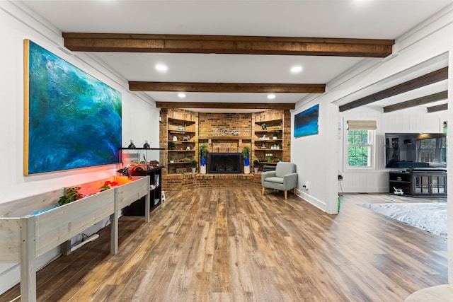 living room with a fireplace, beam ceiling, hardwood / wood-style flooring, and built in features