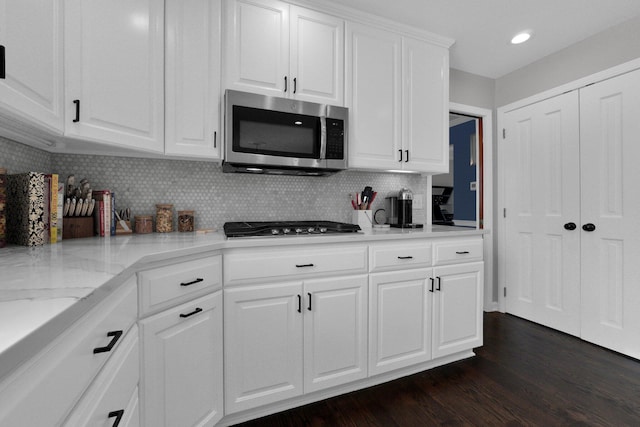 kitchen with white cabinets, light stone countertops, tasteful backsplash, dark hardwood / wood-style flooring, and stainless steel appliances