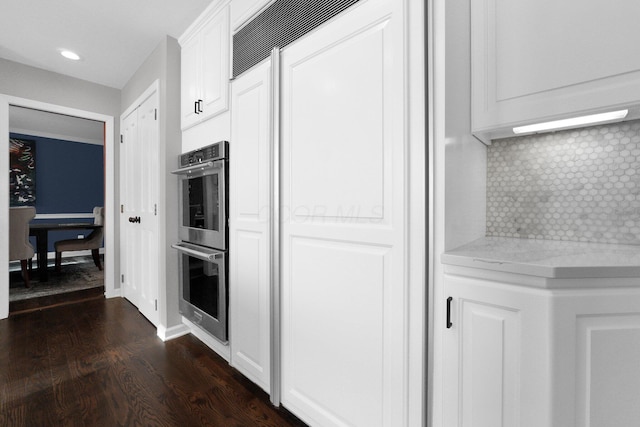 kitchen with light stone countertops, tasteful backsplash, dark hardwood / wood-style floors, double oven, and white cabinets