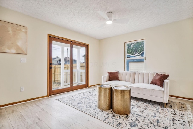 living room featuring ceiling fan, light hardwood / wood-style floors, and a textured ceiling