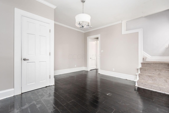 empty room with crown molding, dark hardwood / wood-style floors, and an inviting chandelier