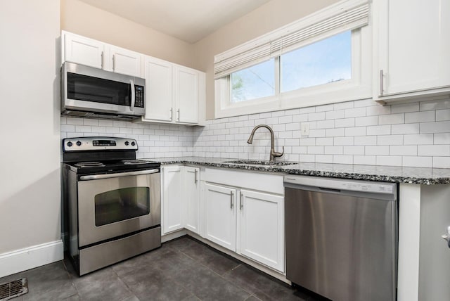 kitchen with dark stone counters, white cabinets, sink, decorative backsplash, and stainless steel appliances