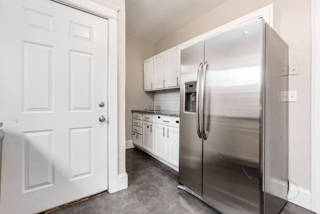 kitchen with white cabinetry, tasteful backsplash, stainless steel fridge with ice dispenser, dark tile patterned floors, and dark stone countertops