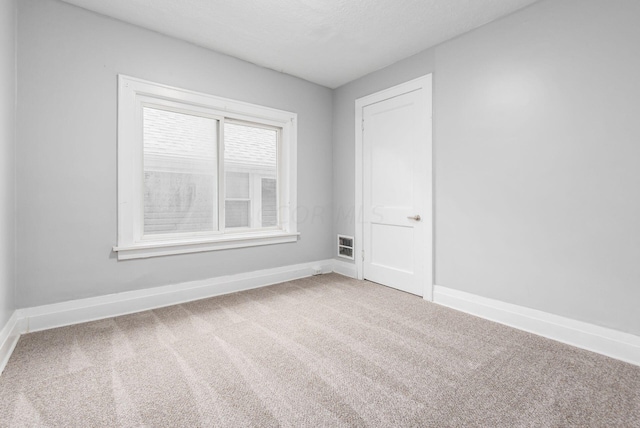 carpeted empty room with a textured ceiling and heating unit