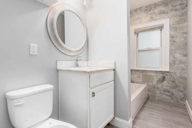 bathroom with a bathing tub, vanity, toilet, and tile walls