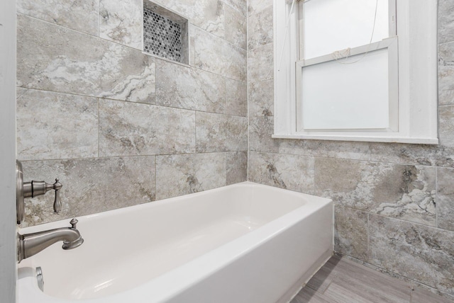 bathroom with a bathtub and tile walls