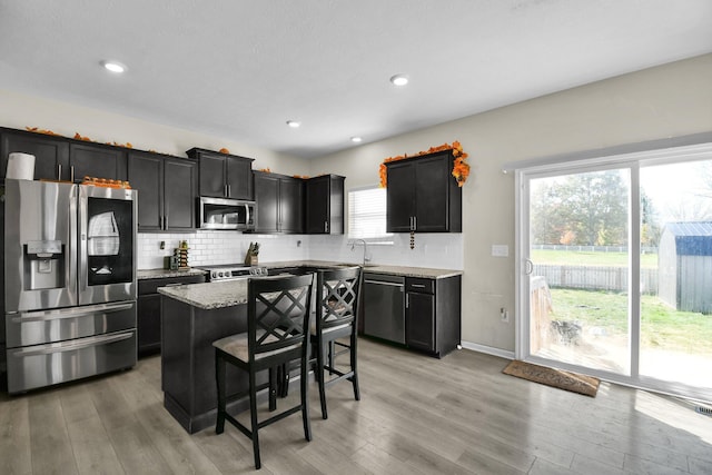 kitchen featuring light stone counters, a center island, light hardwood / wood-style floors, and appliances with stainless steel finishes