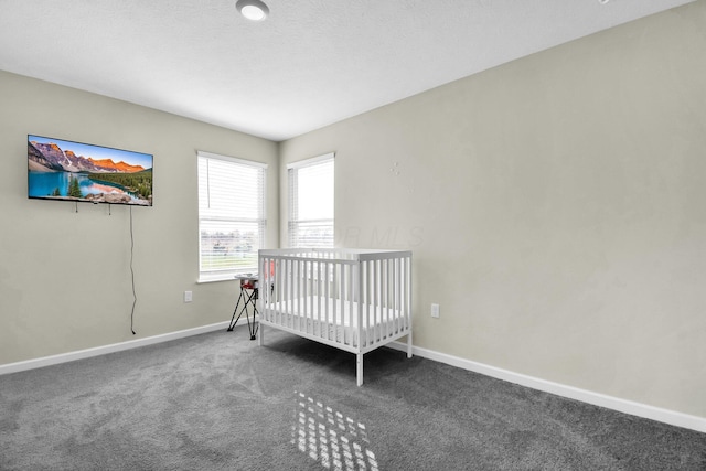 unfurnished bedroom with dark colored carpet and a nursery area