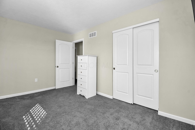 unfurnished bedroom with dark colored carpet and a closet