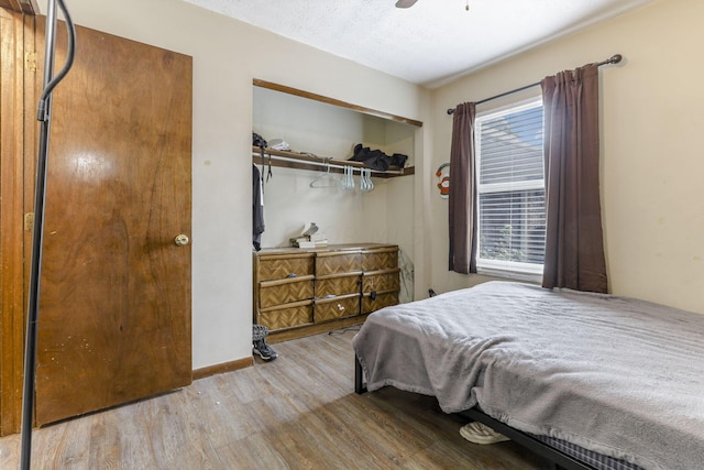 bedroom featuring ceiling fan, light wood-type flooring, a textured ceiling, and a closet