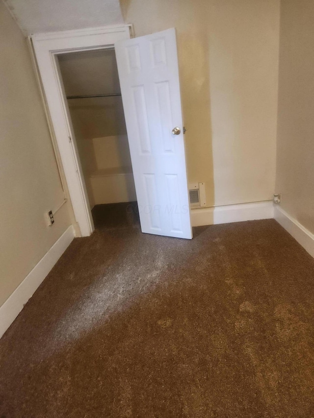 unfurnished bedroom with a closet and dark colored carpet