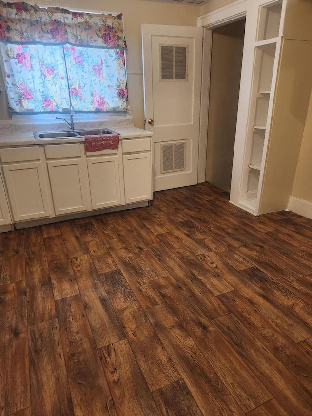 kitchen with white cabinetry, built in features, dark hardwood / wood-style floors, and sink