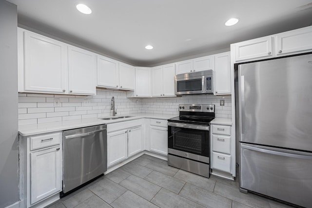 kitchen with white cabinets, decorative backsplash, stainless steel appliances, and sink