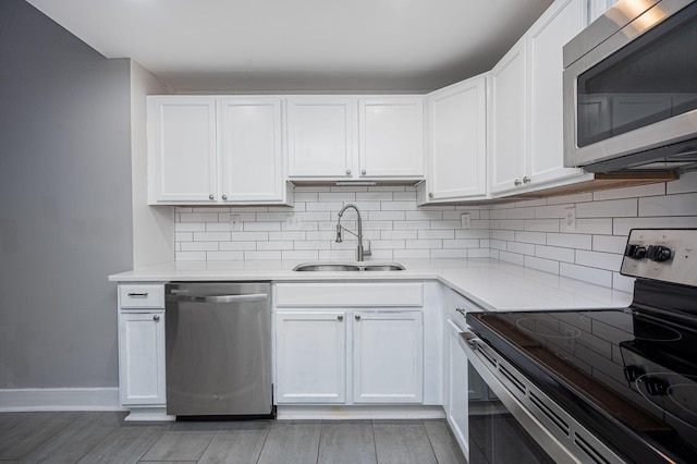 kitchen with appliances with stainless steel finishes, tasteful backsplash, sink, light hardwood / wood-style floors, and white cabinetry