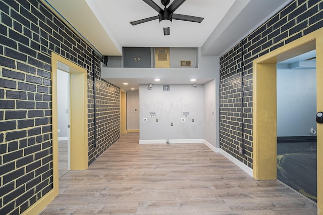 corridor featuring light hardwood / wood-style floors and brick wall