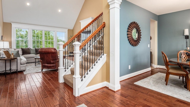 stairway with hardwood / wood-style flooring, ornate columns, and lofted ceiling