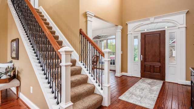 entryway featuring dark hardwood / wood-style flooring, ornate columns, and a high ceiling