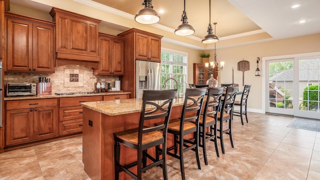 kitchen with stainless steel appliances, pendant lighting, a chandelier, a breakfast bar area, and an island with sink