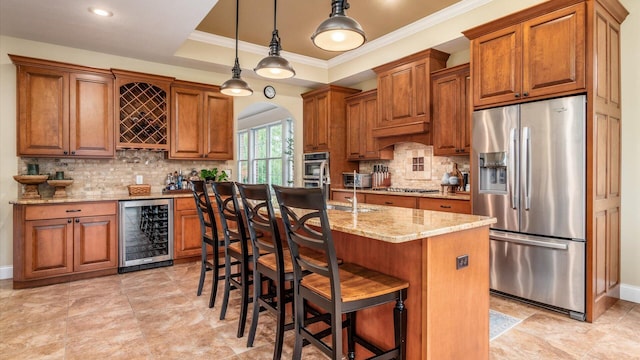 kitchen with a kitchen breakfast bar, wine cooler, pendant lighting, a kitchen island with sink, and appliances with stainless steel finishes