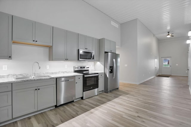 kitchen featuring appliances with stainless steel finishes, light hardwood / wood-style floors, ceiling fan, and sink