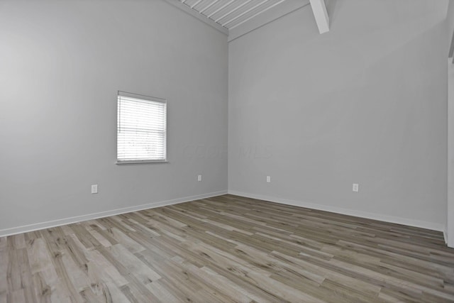 spare room with lofted ceiling with beams and light hardwood / wood-style floors