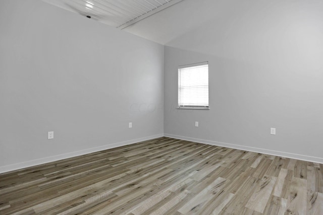 empty room with vaulted ceiling and light hardwood / wood-style flooring