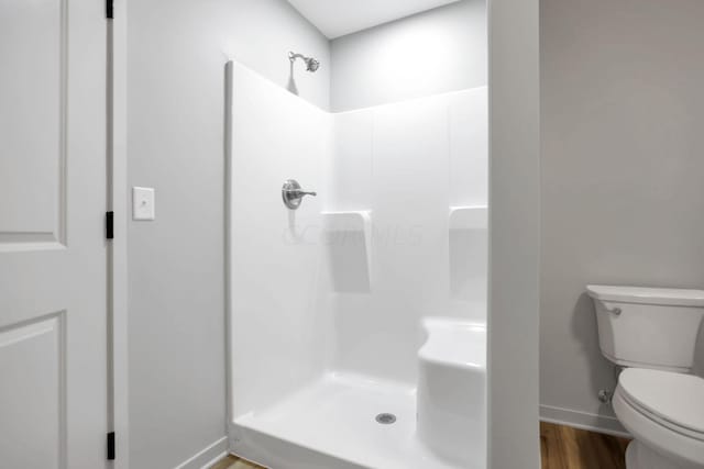 bathroom featuring hardwood / wood-style floors, toilet, and a shower