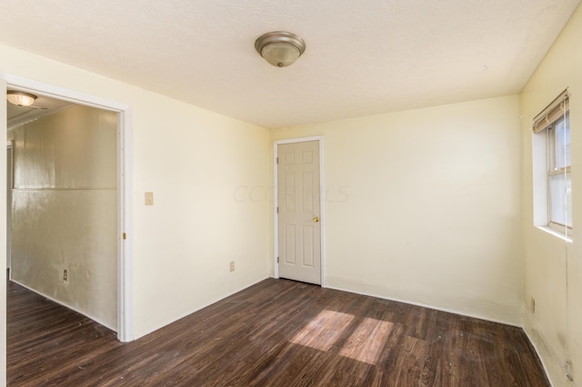 unfurnished room featuring dark hardwood / wood-style flooring and a textured ceiling