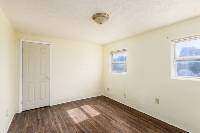 empty room featuring a textured ceiling and dark hardwood / wood-style floors