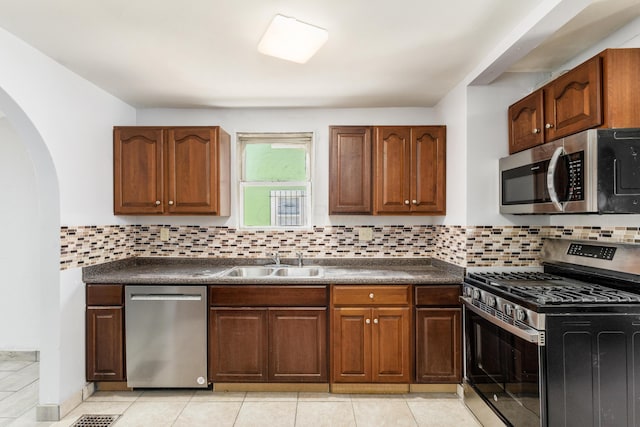 kitchen featuring tasteful backsplash, sink, light tile patterned floors, and stainless steel appliances