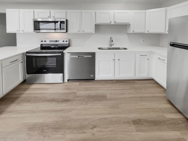 kitchen with sink, white cabinets, light wood-type flooring, and appliances with stainless steel finishes