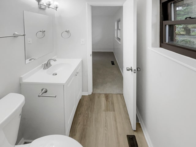 bathroom featuring hardwood / wood-style floors, vanity, toilet, and a notable chandelier