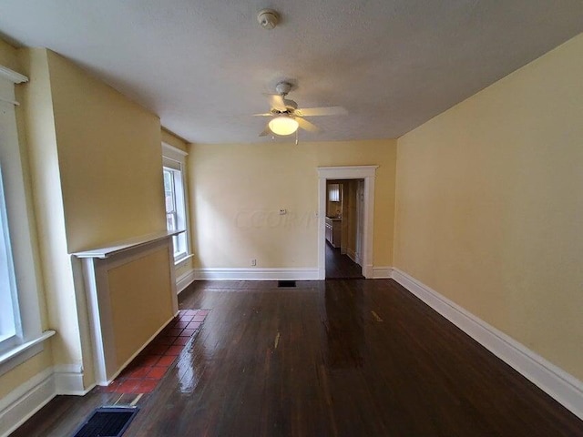 unfurnished room featuring a textured ceiling, ceiling fan, and dark wood-type flooring