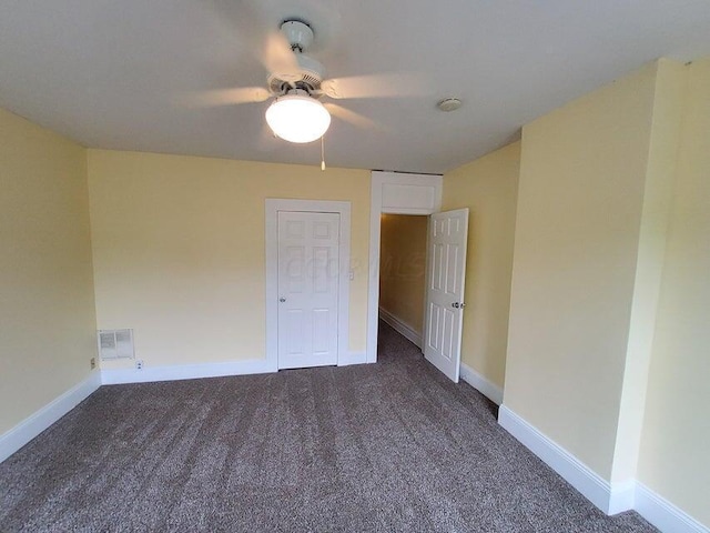 spare room with dark carpet and ceiling fan