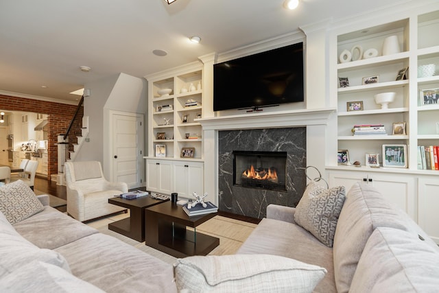 living room with a fireplace, built in shelves, light wood-type flooring, and ornamental molding