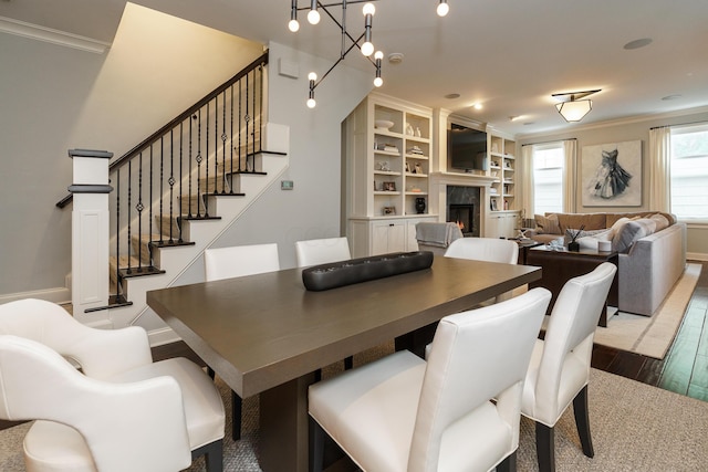 dining area with a chandelier, wood-type flooring, and crown molding