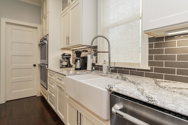 kitchen with sink, stainless steel appliances, light stone counters, dark hardwood / wood-style flooring, and backsplash