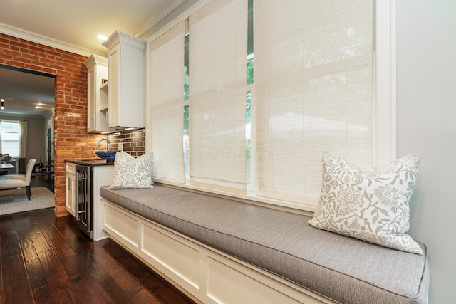 mudroom featuring dark wood-type flooring, brick wall, and ornamental molding