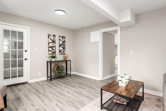 living area featuring a textured ceiling and light hardwood / wood-style flooring