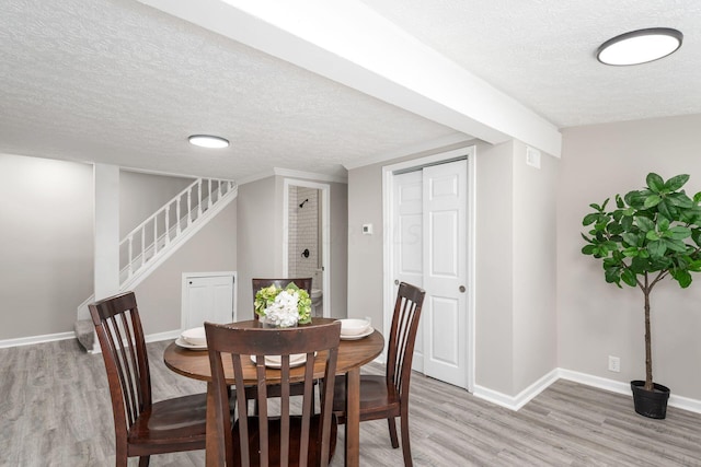 dining room featuring a textured ceiling and light hardwood / wood-style flooring