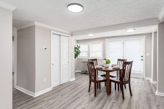 dining area with a textured ceiling, light hardwood / wood-style floors, and crown molding