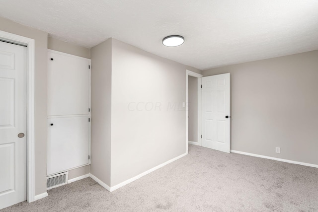 unfurnished bedroom with light carpet and a textured ceiling