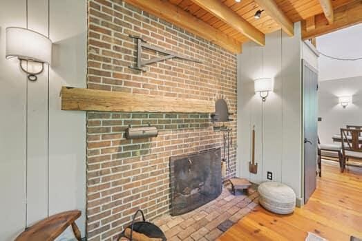 living room with beam ceiling, hardwood / wood-style floors, wood ceiling, and a brick fireplace